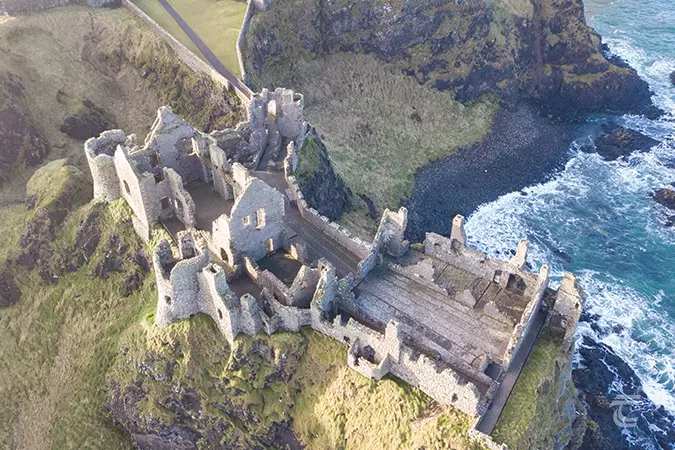Aerial view of Dunluce Castle set on top of a cliff overlooking the Atlantic Ocean