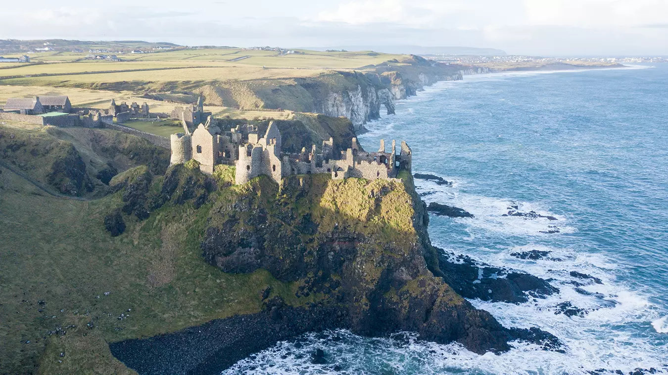 Aerial view of Dunluce Castle perched above the ocean on the Causeway Coast