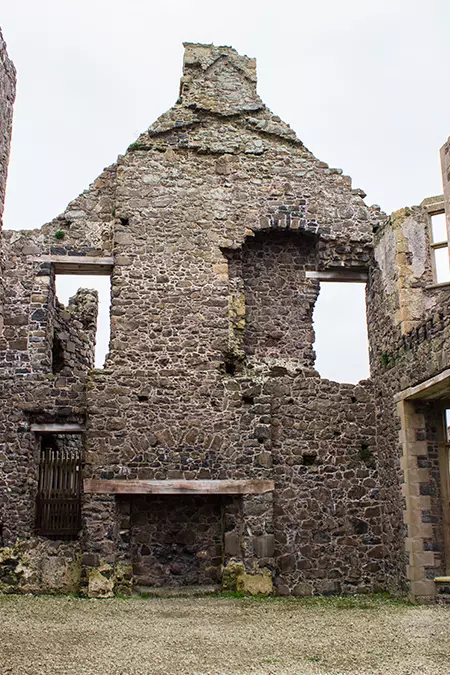 Interior of Dunluce Castle showing fireplace on the ground floor and the sky through the ruins.