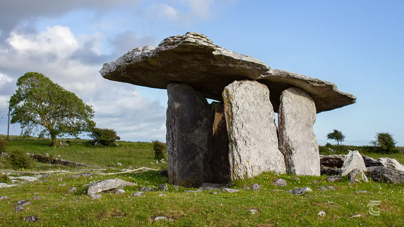 A megalithic tomb stands among green fields in The Burren, Co. Clare
