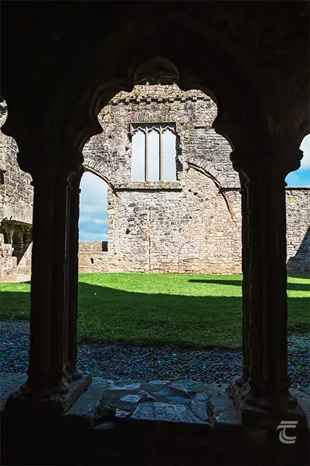 looking through a decorative archway into the 15th century cloister in Bective Abbey, Meath