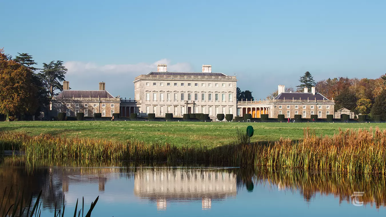 A Palladian mansion surrounded by landscaped gardens and ornamental lake.