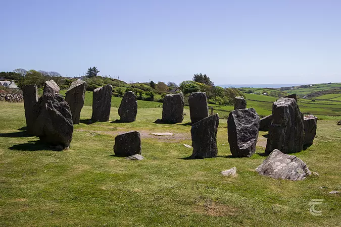 Drombeg Stone Circle in an open field with the Atlantic Ocean visible in the far distance