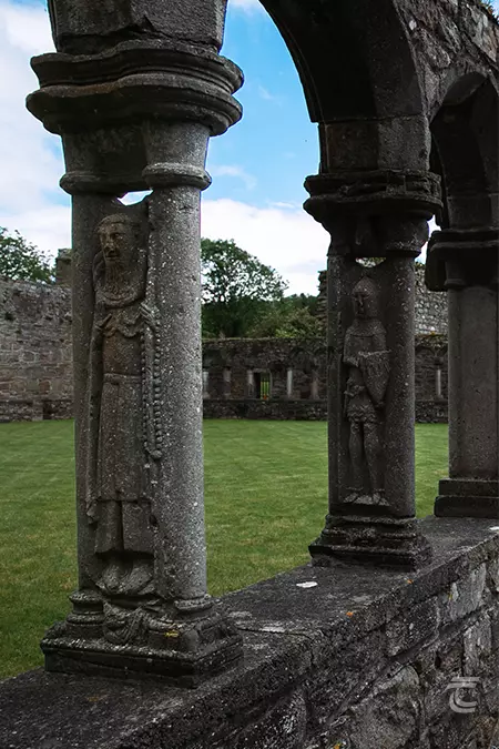 looking into the abbey's cloister. The archway columns contain statues depicting an abbot and a knight