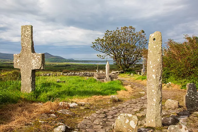 a stone cross and an ogham stone on each side of a stone pathway