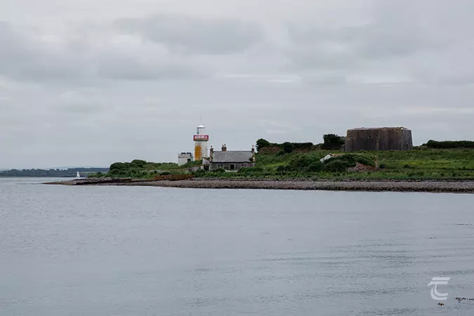 A lighthouse stands on a headland on a cloudy day