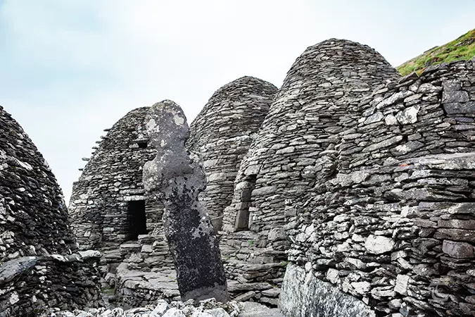 Beehive huts in the monastery on Skellig Michael, with a stone cross at its centre