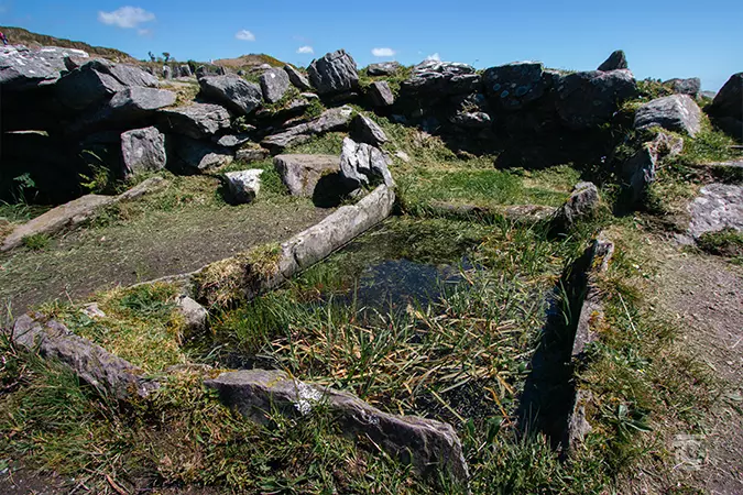 Fulacht fia. A rectangular recess in the ground lined by stone slabs and filled with water.