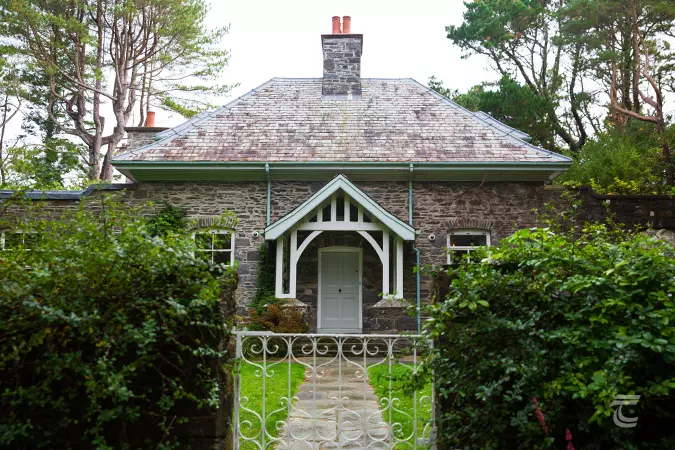 Two-storey cottage with arched porch set amongst a garden