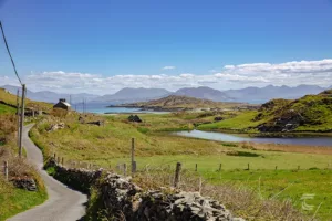 A quiet road leads to St Colmans Monastery on Inishbofin Island with the mountains of Connemara in the background